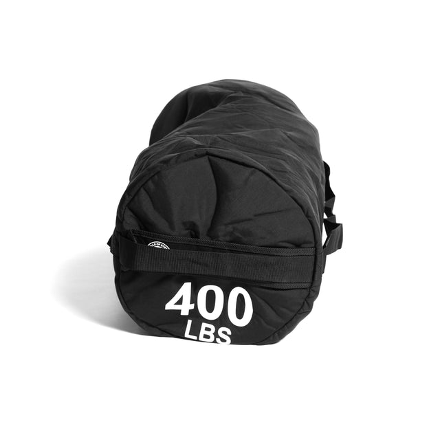 A large black cylindrical Fitness Sandbag from Bells of Steel, crafted with durable Condura construction, comes equipped with side handles and prominently displays "400 LBS" in bold white letters on the end. Ideal for versatile workouts, this sandbag is designed to endure intense training sessions.