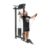 Using the Kraken Rack Attachment for 4 Post Hydra & Manticore Racks by Bells of Steel, a person exercises by pulling handles. They're dressed in a black t-shirt, shorts, and glasses. A plain white background highlights the workout equipment and the person’s posture.