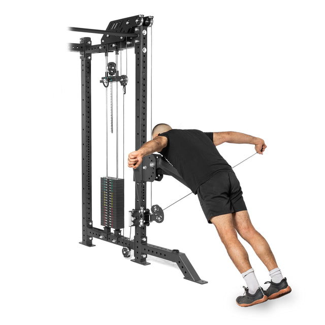 Dressed in black, a person leans forward, gripping the cables of the Kraken Rack Attachment for 4 Post Hydra & Manticore Racks by Bells of Steel. The tall machine features adjustable weights and trolleys for a versatile workout against the white background.