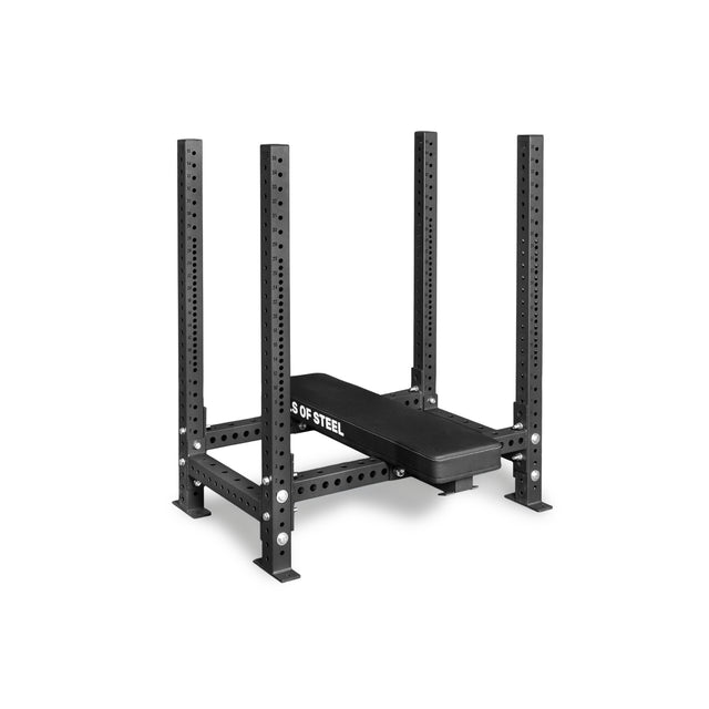 The Hydra Four Post Converter Bench by Bells of Steel USA is a black, rectangular powerlifting station with four vertical posts, multiple adjustment holes, and a padded bench, shown against a plain white background.