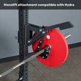 A black monolift attachment is mounted on the Bells of Steel USA Hydra Four Post Converter Bench, holding a loaded barbell with a large red weight plate. The text above reads, "Compatible with Hydra bench press station.