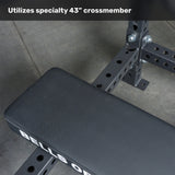 A close-up of the Bells of Steel USA Manticore Four Post Converter Bench shows its metal rack with adjustable holes. Text at the top reads, "Utilizes specialty 43” crossmember." The side of the bench displays "BELLS OF.