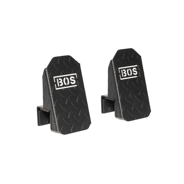 Two black metal hooks with a diamond plate pattern and the white "BOS" logo, designed for wall mounting—perfect as an accessory for the Bells of Steel USA Footplate for Cable Tower/All In One Trainer.