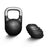 The Bells of Steel Mark Wildman Adjustable Kettlebell in black, featuring a metallic handle and co-designed with Mark Wildman, stands upright beside five round weight plates stacked on their sides, all set against a white background.