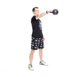 A person in a black t-shirt and Bells of Steel Gym Shorts exercises with a kettlebell, raising it with one hand while balancing on one leg against a white background.