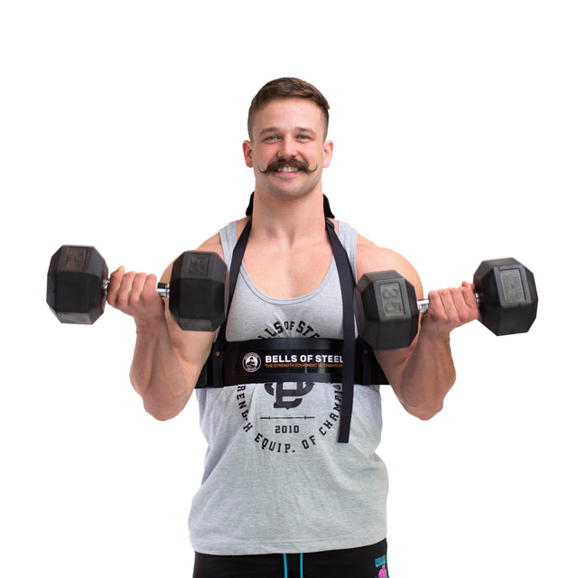 A mustached man in a gray sleeveless shirt performs bicep curls with two dumbbells, using the durable Arm Blaster by Bells of Steel to maintain proper form against a stark white background.