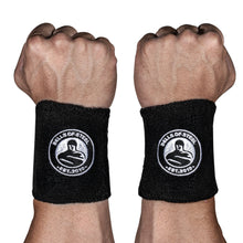 Two fists with wrists facing forward, each wearing Bells of Steel BellGuard Kettlebell Wrist Guards—black guards bearing a circular kettlebell logo and "EST. 2010" in white—essential workout accessories.