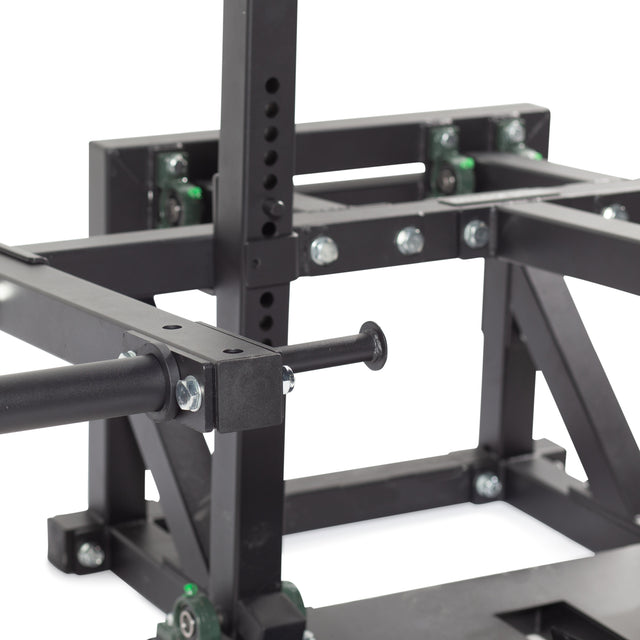 Close-up of a black metal frame with bolts and adjustable parts, part of a home gym setup. It's likely a Belt Squat Machine from Bells of Steel, ideal for building lower body strength, featuring a lever or handle essential for weightlifting exercises.