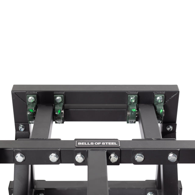 Close-up of the Bells of Steel Belt Squat Machine in black metal, ideal for boosting lower body strength in your home gym. It includes bolts, an adjustable mechanism with green parts, and multiple joints for versatile workouts.