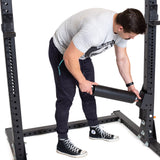 Male athlete setting up Split Squat Leg Roller Rack Attachment on a power rack