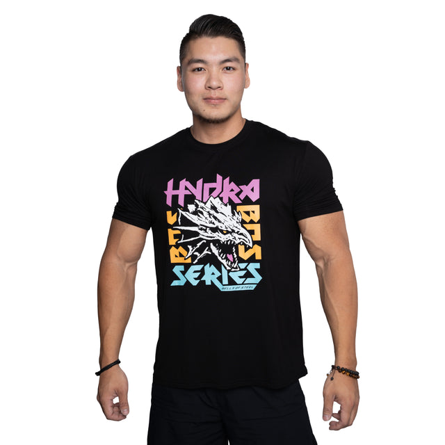 A man with short hair and a neutral expression faces forward, wearing the Bells of Steel Bamboo T-Shirt—a black, sweat-wicking gym shirt with a colorful dragon head graphic and "HYDRA BEAST SERIES" in bold, stylized letters.