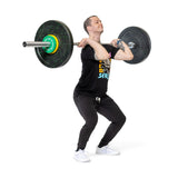 A person in black attire performs a front squat, holding a loaded barbell with Bells of Steel Urethane-Coated Change Plate Sets across their shoulders, maintaining bent knees and a straight back against a plain white background.