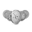 Five Bells of Steel Machined Iron Olympic Weight Plates of different sizes are arranged in a semi-circle, with a 45 lb plate upright in the center. Each plate features precision hole fit and is labeled with its weight and brand name.