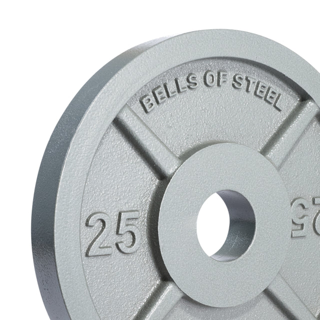 A close-up of a Machined Iron Olympic Weight Plate Set by Bells of Steel, showing the gray plate with "BELLS OF STEEL" and "25" embossed, and a precision center hole for easy barbell mounting.