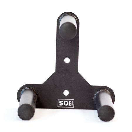 The Bells of Steel Change Plate Storage Pegs is a black metal wall mount bracket with three cylindrical pegs arranged in a triangle, ideal for organizing Olympic change plates. It features two mounting holes and an upside-down "SIS" logo at the bottom.