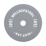 The Bells of Steel Colored Bumper Plates include a grey round design with "BELLSOFSTEEL" and "10 LBS" inscribed, plus "EST. 2010" at the bottom. Its stainless steel insert ensures accurate weight and a perfect fit on barbells.