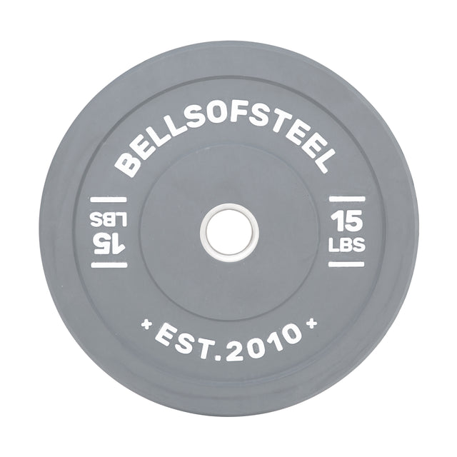 A gray Bells of Steel "Colored Bumper Plates" features a stainless steel insert, printed with "BELLSOFSTEEL," "15 LBS," and "EST. 2010." A lighter gray circle surrounds the center hole for accuracy.