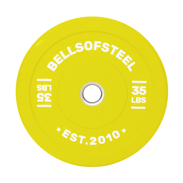 A bright yellow 35-lb Bells of Steel Colored Bumper Plate features "Bells of Steel" at the top, an accurate weight with a stainless steel insert ring, and "Est. 2010" inscribed at the bottom, clearly marked on both sides.