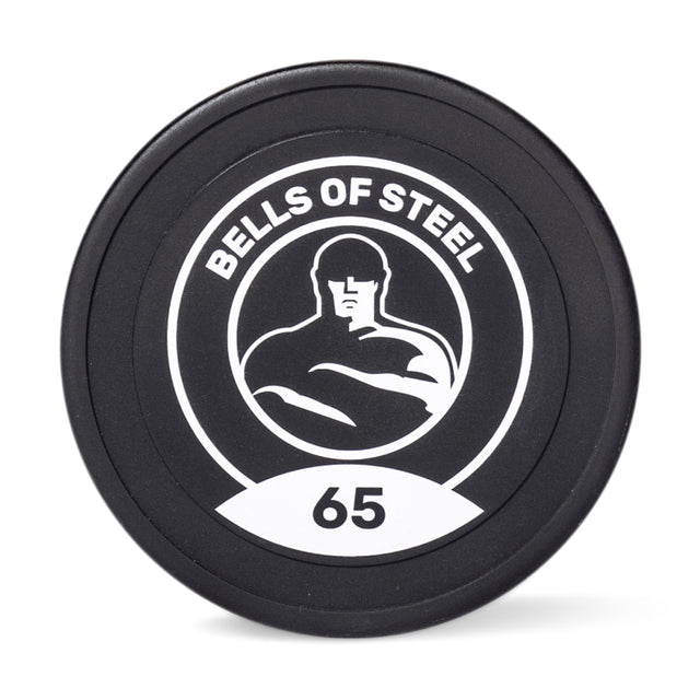 A black weight plate with a white circular logo displaying a muscular silhouette and the text "Bells of Steel" beneath the number "65," represents commercial-grade Urethane Dumbbells.