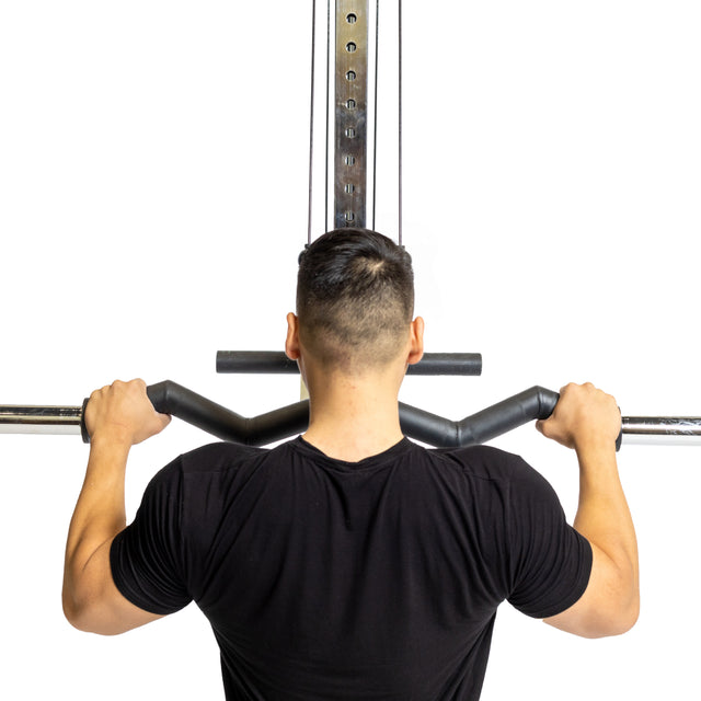 A short-haired individual in a gym wears a black shirt, using the Bells of Steel Fat Bar - Olympic Curl Bar Cable Attachment to lift weights, enhancing their grip strength while facing away from the camera.