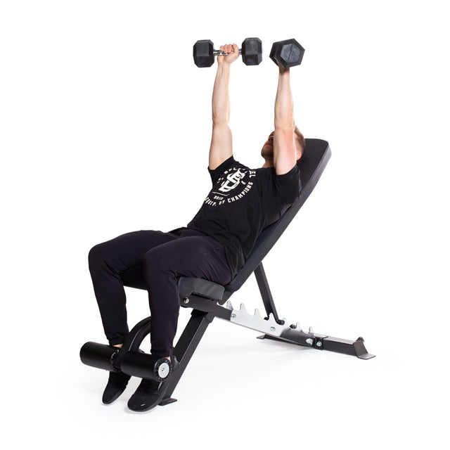 A person is on a bench, doing a bench press with Bells of Steel Ergo Rubber Hex Dumbbells having chrome-plated handles. They're dressed in a black t-shirt and pants, and the bench is inclined against a plain white background.