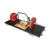 The Bells of Steel Weightlifting Platform features a hex trap bar, striking red weight plates, and an Olympic barbell on a wooden and rubber surface. Ideal for strength training and deadlifting, it includes deadlift pads and is branded with a distinctive logo.