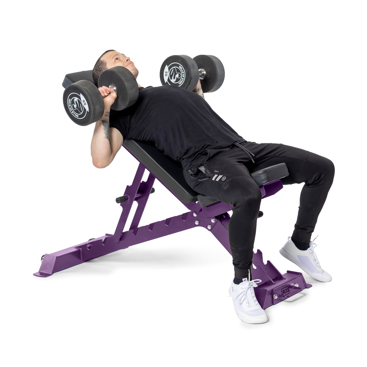 Dressed in a black shirt and pants with white sneakers, the person performs an incline dumbbell press on the Buzz-Saw Heavy-Duty Adjustable Bench by Bells of Steel, against a plain white background.