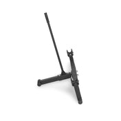 A black guitar stand with dual legs and a tall support arm is captured from the side, echoing the robust design of Bells of Steel's Deadlift Jack with Rollers.