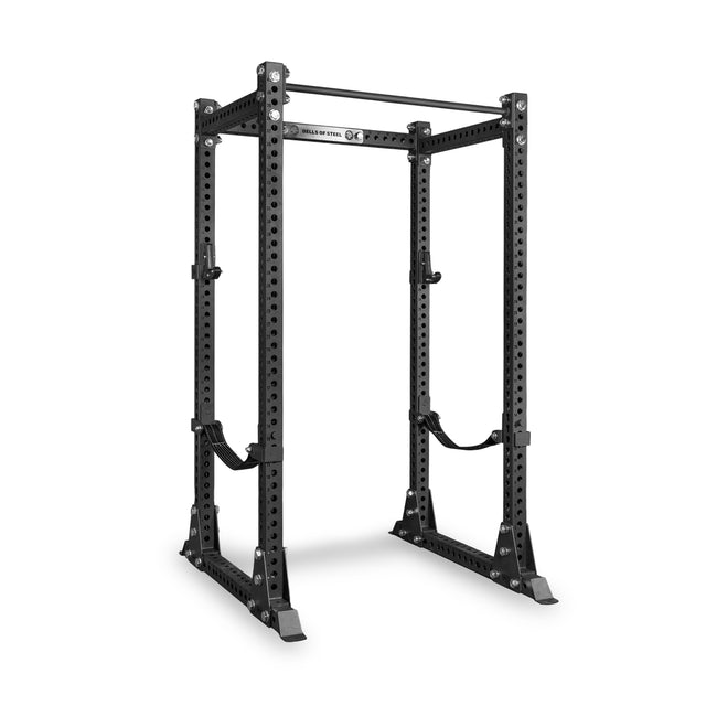Introducing the Bells of Steel Manticore Flat Foot Power Rack Builder (3" x 3", 1" Holes)—a sturdy, black metal power rack designed for weightlifting. It features multiple adjustment holes, a pull-up bar on top, and safety straps on each side. This robust 3x3 power rack stands securely on four wide, stable feet, making it the ideal centerpiece for any home gym.