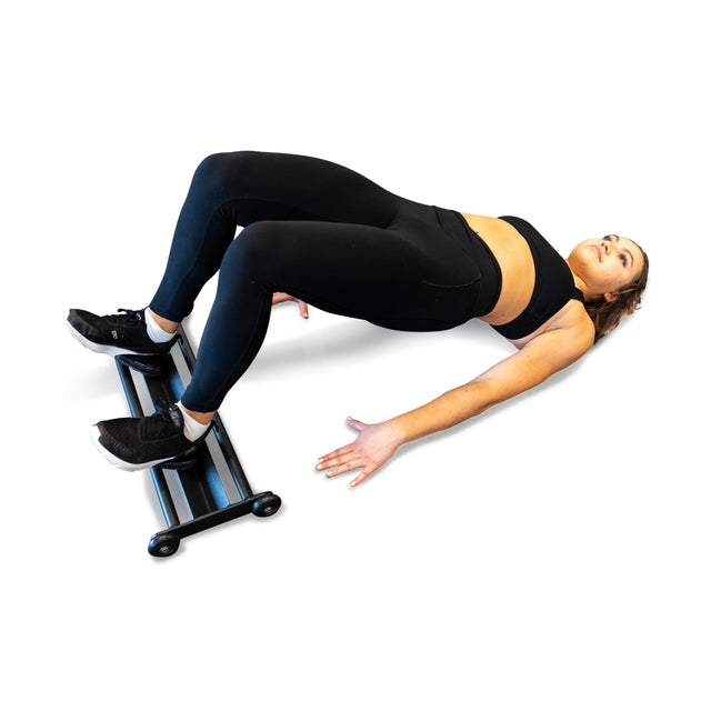 An athlete showcases the Bells of Steel Glute Ham Slider, performing a glute bridge with feet on the slider, easily engaging in hamstring exercises against a plain white background.