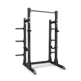 Introducing the Bells of Steel Manticore Half Rack Builder (3" x 3", 1" Holes)—a black metal power rack featuring sturdy 3x3 uprights, adjustable safety bars, integrated pull-up bar, and convenient weight plate holders. Expertly designed for strength training and weightlifting in your home gym.