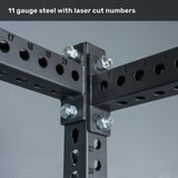 Close-up of intersecting black Manticore Half Rack Builder uprights (3" x 3") from Bells of Steel, featuring circular 1" holes and precision laser-cut numbers, all secured by large bolts. Text above reads, "11 gauge steel with laser cut numbers"—perfect for building a sturdy half rack in your home gym.