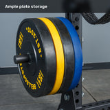 Three large weight plates—black, yellow, and blue—are stacked on a gym plate holder attached to the Bells of Steel Manticore Half Rack Builder (3" x 3", 1" Holes), whose robust uprights make it an excellent addition to any home gym. The text "Ample plate storage" appears at the top.