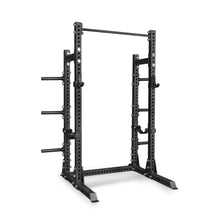 Introducing the Bells of Steel Manticore Half Rack - Prebuilt: a sleek black, heavy-duty metal rack featuring 3" x 3" uprights with 1" holes for versatile attachments, adjustable safety bars, an integrated pull-up bar on top, and plate holders on the sides—an ideal choice for weightlifting and strength training in your home gym.