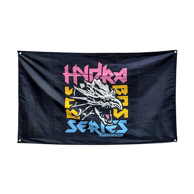 The Bells of Steel flag displays a striking dragon head with an open mouth, surrounded by bold pink, yellow, and blue "Hydra Bass Series" text on black. Ideal for accentuating your home gym decor.