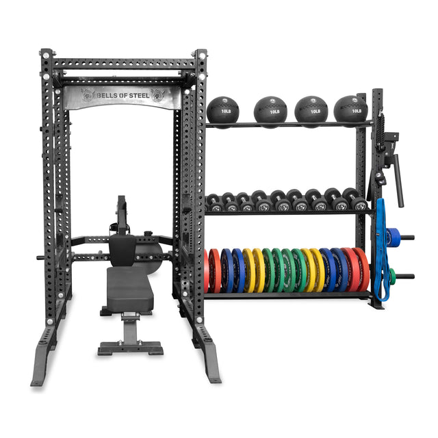 Bells of Steel's Hydra Storage Builder is a modular system showcasing a power rack with a bench, barbells, and kettlebells on top shelves. It maximizes vertical storage with dumbbells on middle racks and colorful weight plates below to keep strength training equipment organized.