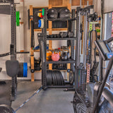 The Bells of Steel Hydra Storage Builder features a versatile home gym setup with kettlebells, weight plates, a barbell, medicine balls, resistance bands, and a functional trainer. It includes a modular storage system with shelves and racks on rubber flooring for efficient organization. .