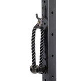 A black tricep rope with rubber ends hangs from a Bells of Steel Utility Hook on a metal gym rack with numbered holes, demonstrating organized storage for cable attachments.