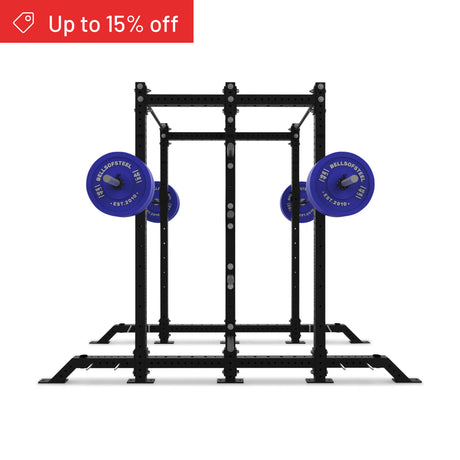 The Bells of Steel Hydra 2-Sided Rack, in black, is ideal for a home gym and comes with two sets of blue barbells. A red banner at the top left corner reads "Up to 15% off" against a white background.