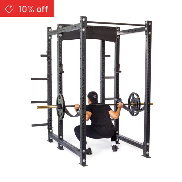 A person in black workout clothes does a squat with a barbell inside the Bells of Steel Hydra Six Post Power Rack Builder (3" x 3", ⅝" Holes). A red banner in the top left corner displays "10% off.