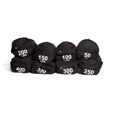 Seven black Bells of Steel Fitness Sandbag Sets, each labeled with weights from 50 to 400 lbs, are arranged in two rows against a white background, highlighting their durable construction—ideal for intense workouts.