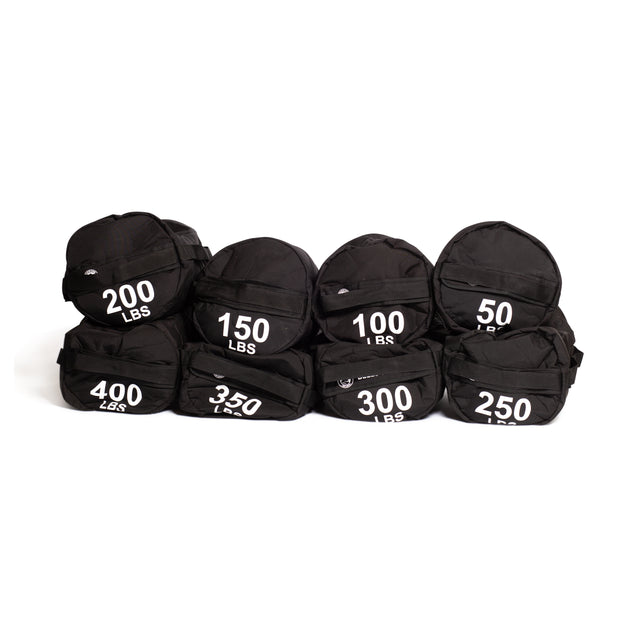 Seven black Bells of Steel Fitness Sandbag Sets, each labeled with weights from 50 to 400 lbs, are arranged in two rows against a white background, highlighting their durable construction—ideal for intense workouts.