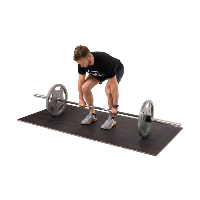 A person in athletic clothing prepares to lift a barbell on Bells of Steel's Rubber Flooring Gym Mat 39" x 39", designed for sound dampening and stability with its recycled rubber. Gripping the bar firmly, they are positioned in a bent-over stance.