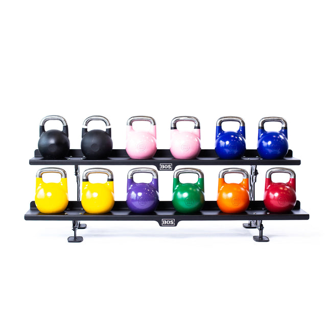 The Bells of Steel Commercial Interchangeable Weight Rack - Components Only features a two-tier design with a swappable shelf, holding twelve competition kettlebells in black, pink, blue, yellow, green, orange, and red in two neat rows.