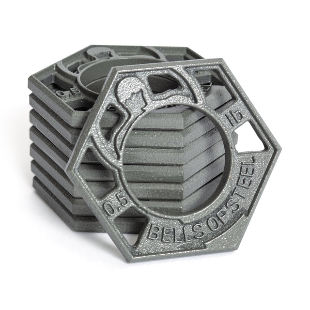 A stack of five gray, hexagonal cast iron plates with a skeletal design featuring "Bells of Steel" text. Each Fractional Iron Plate - 0.5 LB fits an Olympic barbell, highlighted by its textured surface.