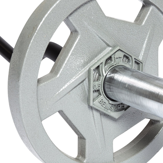 Close-up of a Bells of Steel Fractional Iron Plate - 0.5 LB on an Olympic barbell, showcasing engraved details and a small metal collar. The cast iron plate, featuring a five-spoke design, is set against a plain white background.