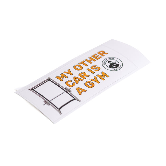 The Bells of Steel Stickers feature a rectangular white design with bold orange text, "MY OTHER CAR IS A GYM," alongside a power rack illustration and circular logo. Made with quality adhesive backing, this durable sticker stays put wherever displayed.