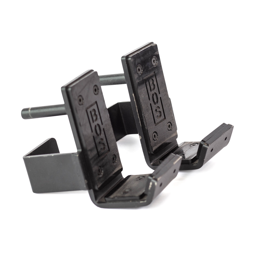 The Bells of Steel Standard J-Cups are black metal attachments for power racks, featuring "BOS" engraving, padded UHMW protection, and durable construction to securely support barbells during workouts.