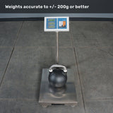 A Bells of Steel Competition Kettlebell rests on the platform of a digital scale, which clearly displays its weight for easy reference when using a kettlebell weight guide. Text above states, “Weights accurate to +/- 200g or better.” The scale is positioned on a tiled floor.