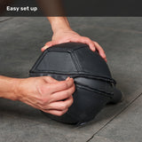Hands zip a black, polygonal leather Bells of Steel USA Kettlebell Wrap over an object on a gray stone floor beneath the text “Easy set up.”.